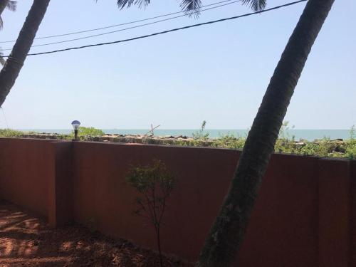 a wall with two palm trees in front of it at Kizhunna rock beach house in Kannur