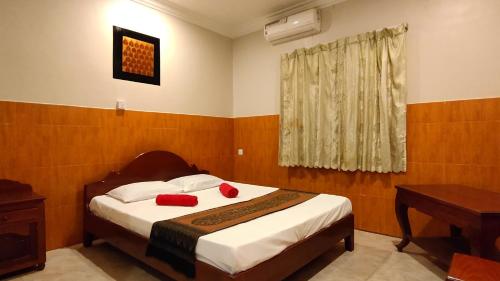 1 dormitorio con 1 cama con 2 almohadas rojas en White Monkey en Siem Reap