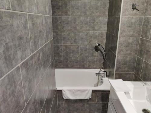 a bathroom with a white tub and a sink at Hotel Les Voyageurs - Vogüé in Vogüé