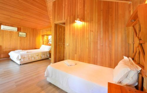 a bedroom with two beds and wooden walls at Arcadia Hotel in Cıralı