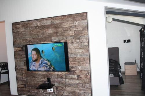 TV de pantalla plana montada en una pared de ladrillo en Квартира-студия в ЖК Ботанический сад 10 мкр, en Aktau