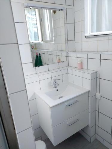 une salle de bain blanche avec un lavabo et un miroir dans l'établissement Appartement confortable à Rosny-sous-Bois, 38m² + Vue sur la ville, à Rosny-sous-Bois