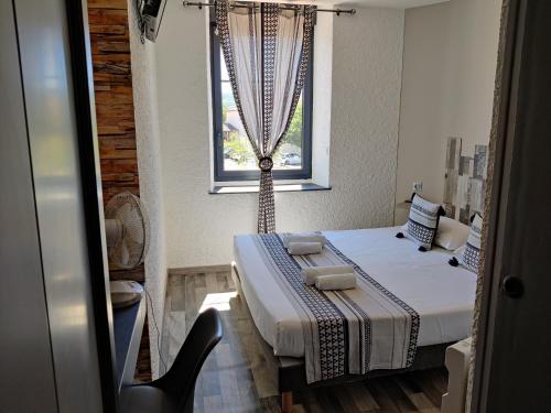 a small room with a bed and a window at Hotel Les Voyageurs - Vogüé in Vogüé