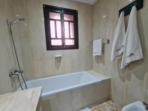 a bathroom with a bath tub and a window at Targafit Hotel & Hammam in Marrakech