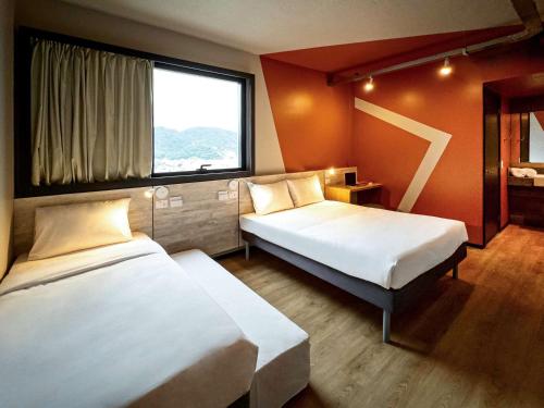 um quarto de hotel com duas camas e uma janela em Ibis Budget Balneario Camboriu em Balneário Camboriú