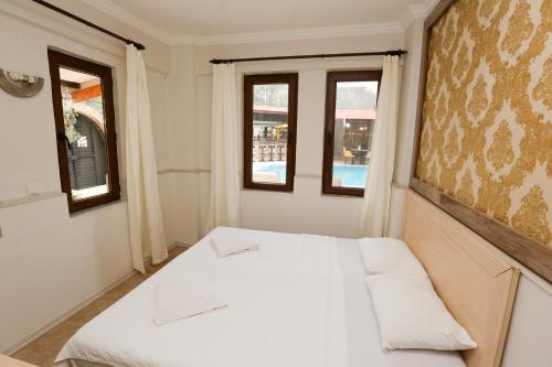 Cama blanca en habitación con 2 ventanas en Dalyan M Otel en Dalyan
