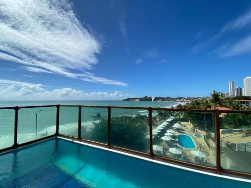 a balcony with a swimming pool overlooking the ocean at Araçá Praia Flat - Ponta Negra in Natal