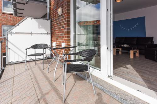 d'une terrasse avec 2 chaises et une table sur un balcon. dans l'établissement Nordseegartenpark Friesenstolz, à Bensersiel