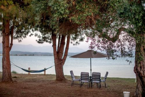 zwei Stühle und ein Sonnenschirm am Strand in der Unterkunft Kiani Akti Villas in Preveza