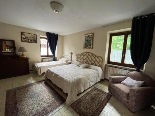 1 dormitorio con 2 camas y 1 silla en Il gufo e il gatto del lago, en Travedona