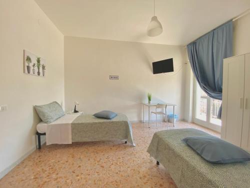 a room with two beds and a table and a television at Guest House Service - Modugno in Modugno