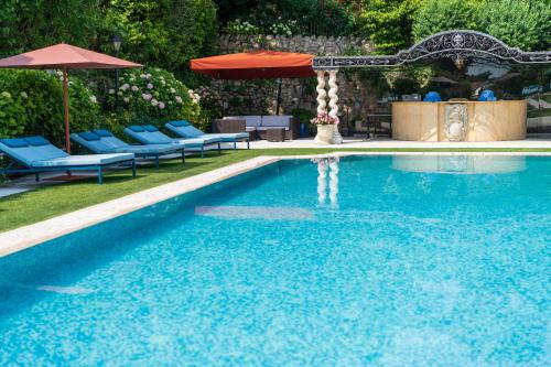 a swimming pool with blue chairs and an umbrella at Byblos Art Hotel Villa Amistà in San Pietro in Cariano