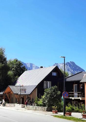 a black building with a tin roof on the side of a street at Apartments center Zorić in Žabljak