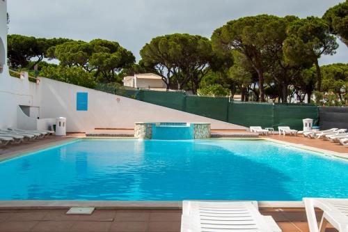 a large swimming pool with chairs and trees at Açoteias B3 in Albufeira