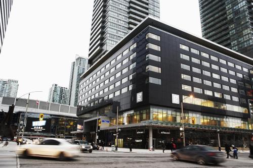 فندق لو جيرمان مابل ليف سكوير في تورونتو: مبنى اسود كبير في مدينة بها سيارات