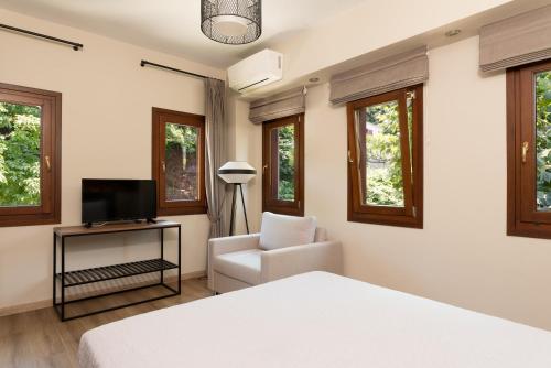 a bedroom with a bed and a chair and a television at Άλυσσος suites in Tsagarada
