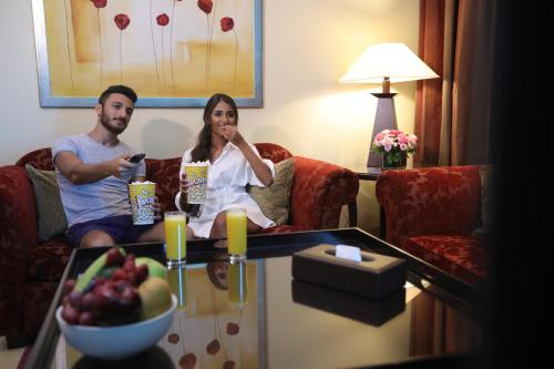 a man and woman sitting on a couch in a hotel room at Raouche Arjaan by Rotana in Beirut