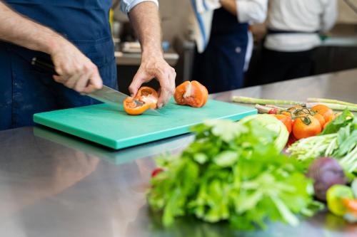 a man cutting up a tomato on a cutting board at Byblos Art Hotel Villa Amistà in San Pietro in Cariano
