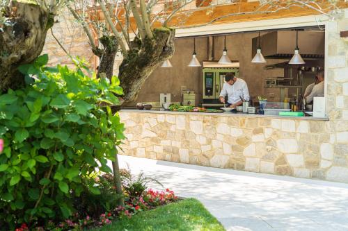 a chef preparing food in a kitchen behind a stone counter at Byblos Art Hotel Villa Amistà in San Pietro in Cariano