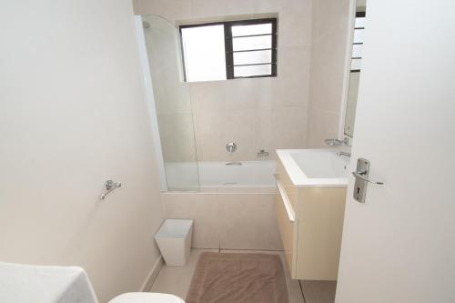 a white bathroom with a sink and a toilet at 7 The Shades Umhlanga Rocks in Durban