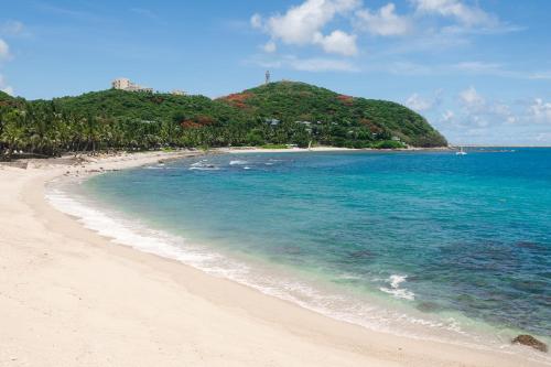 a beach with a hill in the distance and the ocean at Mandarin Oriental, Sanya in Sanya