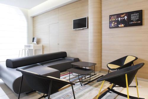 a living room with a black couch and chairs at Novotel Brussels Centre Midi in Brussels