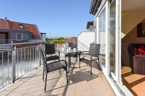 d'une terrasse avec des chaises et une table sur un balcon. dans l'établissement Nordseegartenpark Friesenstolz, à Bensersiel