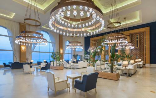 a lobby with tables and chairs and chandeliers at Royal Tulip Korbous Bay Thalasso & Springs in Qurbuş