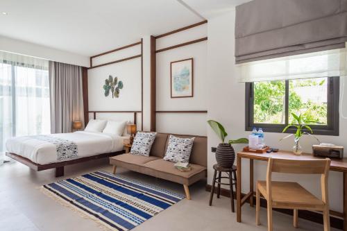 a bedroom with a bed and a table and a desk at Baan Kamana Guest House in Phangnga