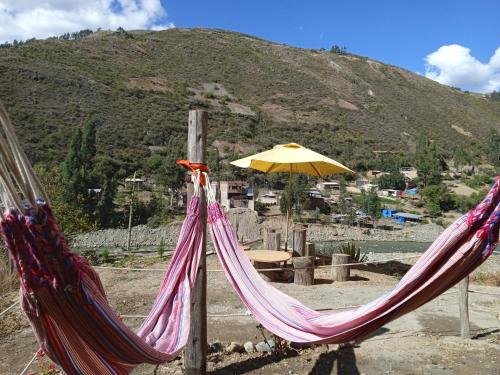 two hammocks and a yellow umbrella on a mountain at Ecolodge Casa del Montañista in Huaraz