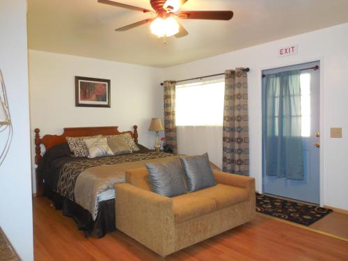a bedroom with a bed and a couch and a ceiling fan at Yosemite Paradise Inn in Coulterville