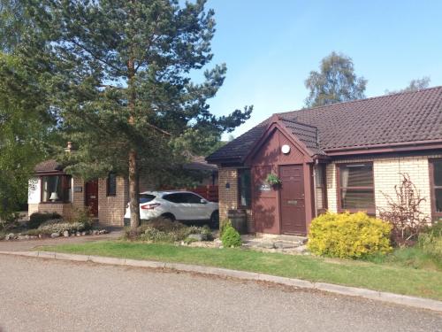 a house with a car parked in front of it at Aviemore Glenlivet Lodge in Aviemore
