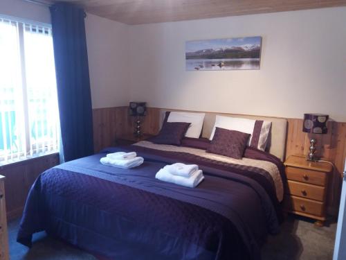 a bedroom with a bed with two towels on it at Aviemore Glenlivet Lodge in Aviemore