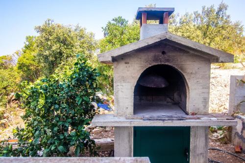 an outdoor pizza oven sitting next to a bush at Apartment Zvonimir in Nečujam