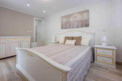 een witte slaapkamer met een bed en twee nachtkastjes bij Villa Green Point in Grižane