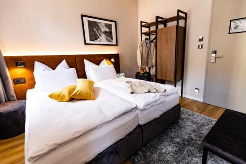 バート・クロイツナハにあるBC Hotel Bad Kreuznach mit Restaurant Mühlentorのベッドルーム1室(白いシーツと黄色い枕の大型ベッド1台付)