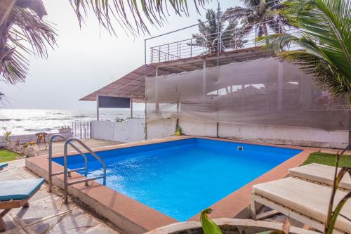 une grande piscine à côté de l'océan dans l'établissement Beachfront pool villa Myconos, à Anjuna