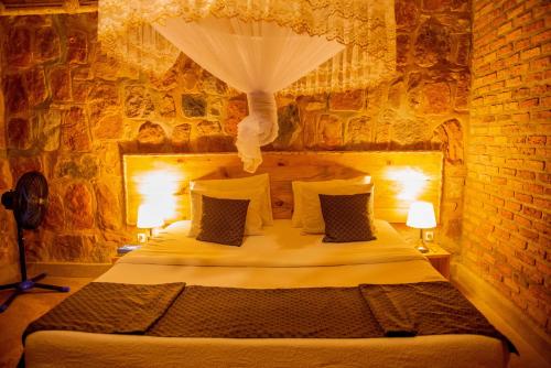 a bedroom with a large bed in a brick wall at Akagera Transit Lodge in Akagera