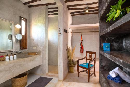 a bathroom with a sink and a chair at Villa Lala in Kiwengwa