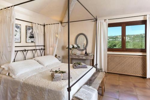 a bedroom with a bed and a mirror and a window at Villa Hortensia in Arzachena