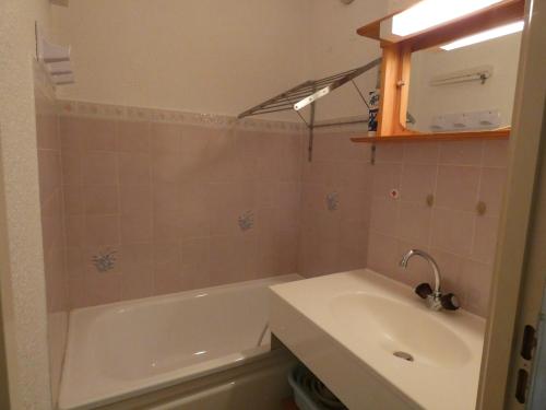 een badkamer met een wit bad en een wastafel bij Appartement typique de montagne in Thollon