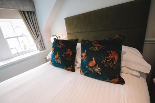 a bed with pillows and pillows on top of it at The Seafield Arms-Cullen in Cullen