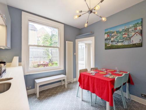 a dining room with a red table and a window at No Five - Worthing in Worthing