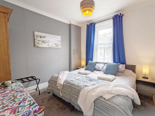 a bedroom with a bed and a window with blue curtains at No Five - Worthing in Worthing