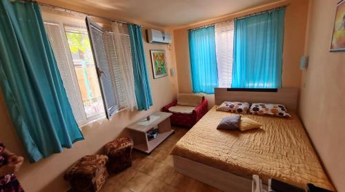 a bedroom with a bed and a chair and windows at Sadala Guest House in Nesebar