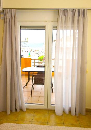 a room with sliding glass doors with a table and a balcony at Dolphins Apartments in Loutra Edipsou