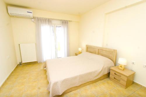 a bedroom with a white bed and a window at Dolphins Apartments in Loutra Edipsou