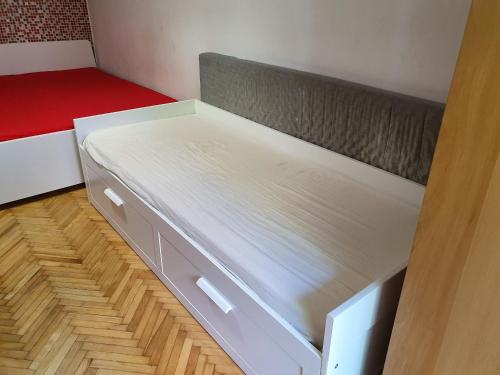 Heroes Square & City Park Thermals Apartment في بودابست: سرير في غرفة صغيرة مع مرتبة حمراء