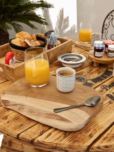 een houten tafel met een dienblad met een glas sinaasappelsap bij La Suite Côté Pool-House Piscine, Sauna & Jacuzzi privatifs in Istres
