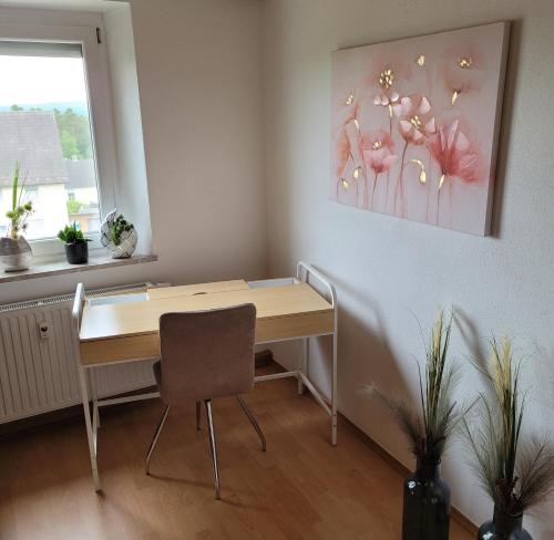 a desk with a chair and a picture on the wall at Ferienwohnung Melanie Wackersdorf in Wackersdorf